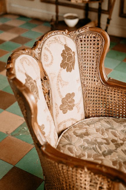 Close-up of an antique green upholstered sofa with an ornate wooden frame, situated against a plain, light-colored textured wall in a residential room. The fabric on the sofa appears clean and well-ma